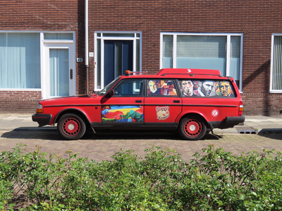 912722 Afbeelding van een rode stationcar met afbeeldingen van filmsterren en Freddie Mercury op de achterruiten en een ...